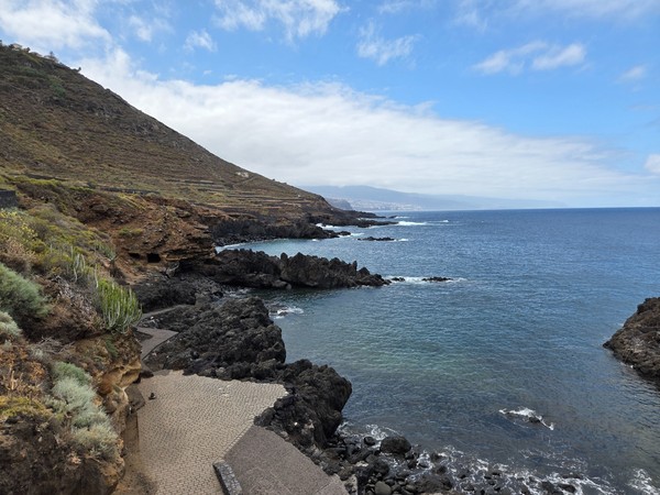 View along the north coast showing layered cliffs, headlands and calm Atlantic waters.