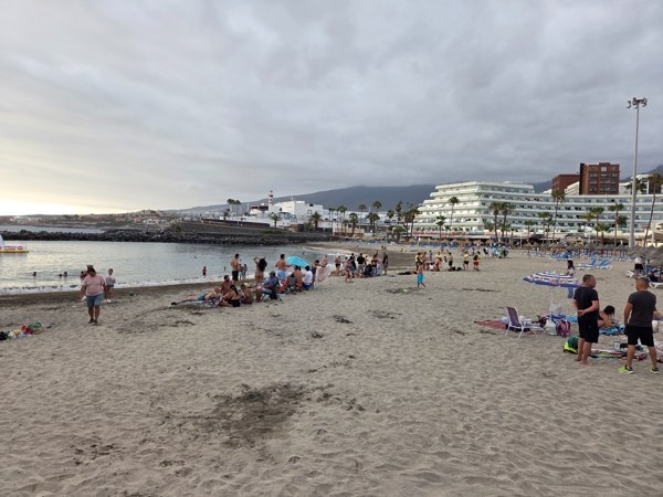 Wide sandy arc of Playa La Pinta by the marina on a cloudy afternoon.