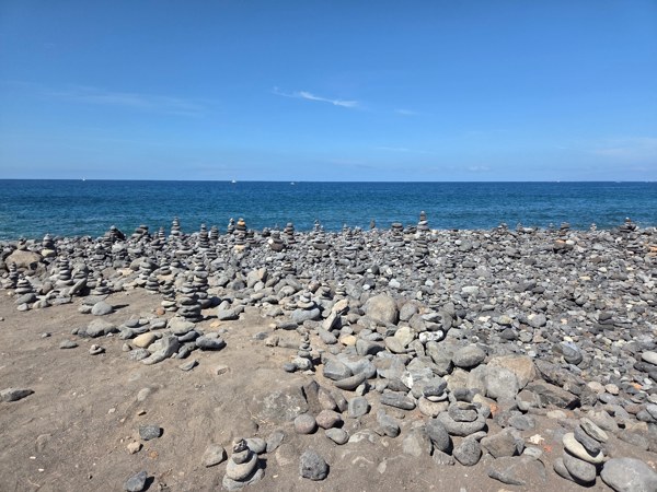 Dozens of small stone cairns stacked along the volcanic shore of Costa Adeje.