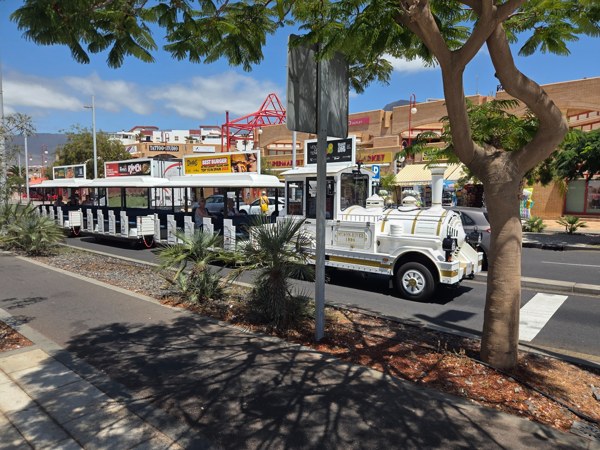 White tourist road train running between Costa Adeje resort areas.