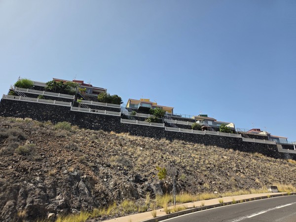 Terraced villas in Costanera built above dark volcanic retaining walls on the cliff.