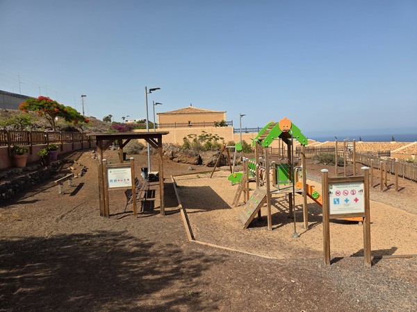 Children’s playground in Costanera with slides and climbing elements in a fenced area.
