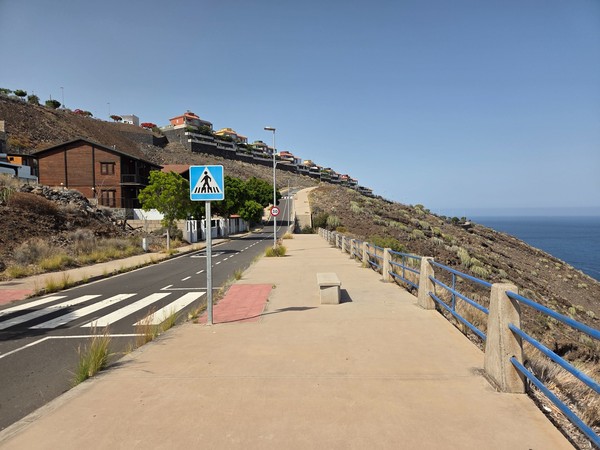 Seafront promenade in Costanera with blue railings, crosswalk and benches overlooking the Atlantic.