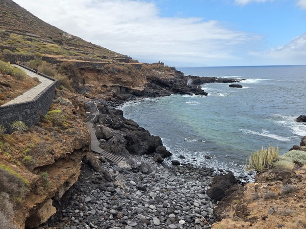 Zigzag stairway between lava rocks offering safe access toward the rocky shoreline below the promenade.
