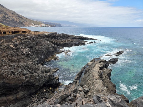 Clifftop view toward jagged lava platforms and turquoise water along the Costa El Sauzal shoreline.