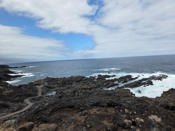 Tide-fed rock pools connected by a boardwalk across black basalt at Costa El Sauzal.