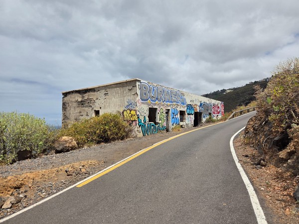 Graffiti-covered ruin on a narrow road with ocean views near El Sauzal.