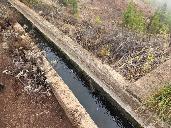 Narrow concrete irrigation channel carrying water along the slope near El Contador.