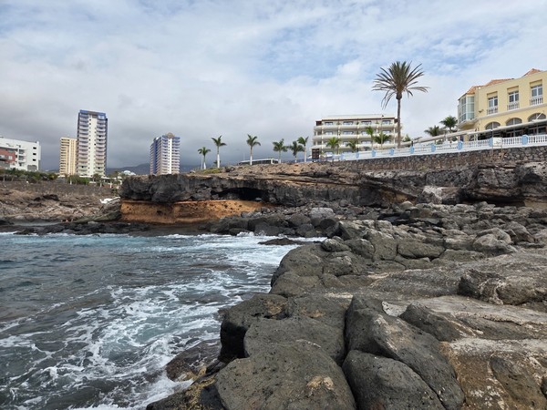 View back toward Costa Adeje with hotels and palm trees rising above the rocky coves of El Marquéz.
