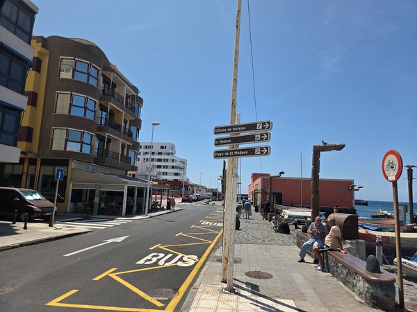 Directional signs pointing to the tourist office, El Médano beach and nearby hotels beside the waterfront bus bay.