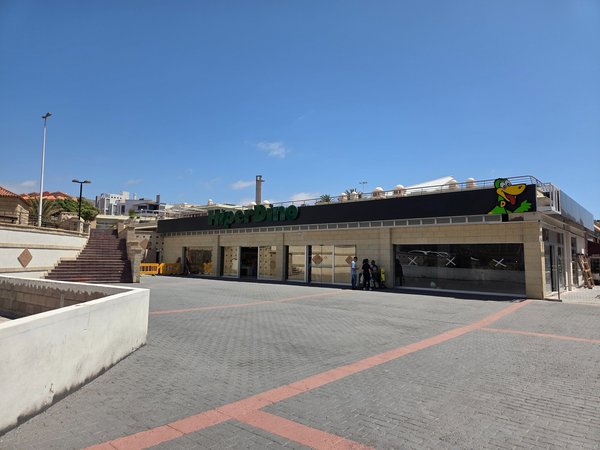Hiperdino supermarket set below a spacious plaza—handy for picnic supplies.