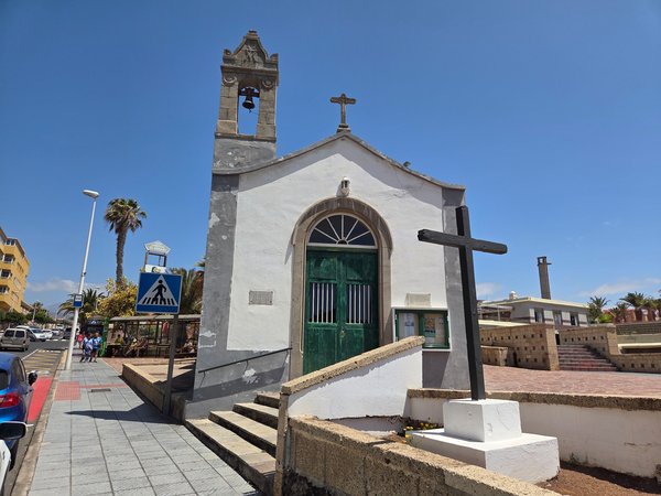 Small seaside chapel of Nuestra Señora de las Mercedes with its bell tower and cross.
