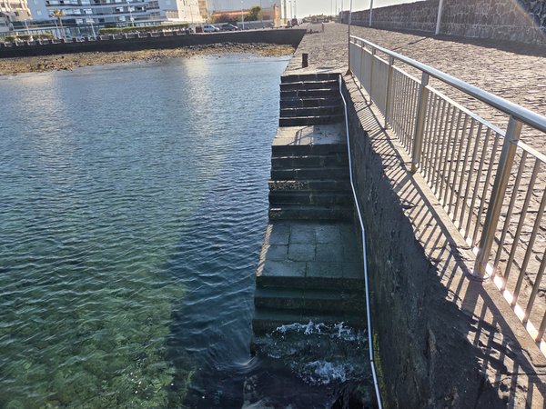 Stone steps descending from the town pier into clear Atlantic waters—perfect for a refreshing dip.