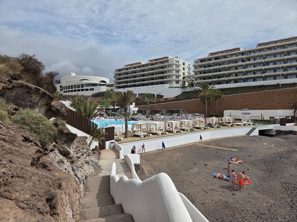 Sunbeds and lagoon-style pool of the nearby resort above Playa El Pinque.
