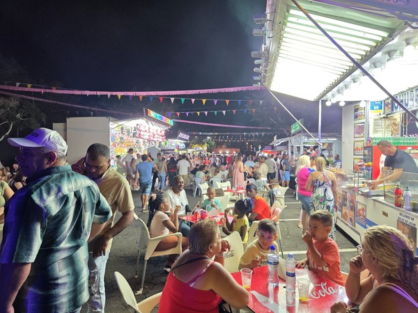 Family area with snack stands and prize booths along the illuminated fair street at the El Fraile festival.