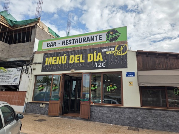 Entrance of Bar Restaurante bp Guaza in Tenerife with a sign promoting menu of the day above the door.