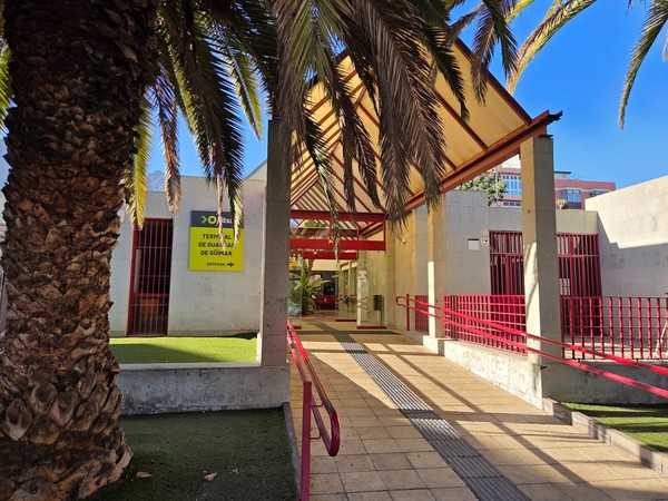 Covered platforms of the Güímar bus station with people waiting on benches and colourful painted walls.