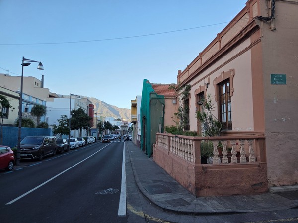 Long residential street in Güímar with an old house in the foreground and mountains visible at the end of the road.