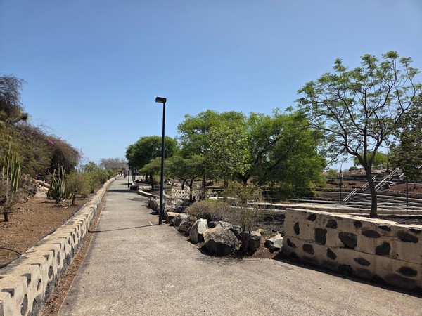 Long, level promenade with lamp posts and stone edging running above the landscaped terraces of La Higuera.