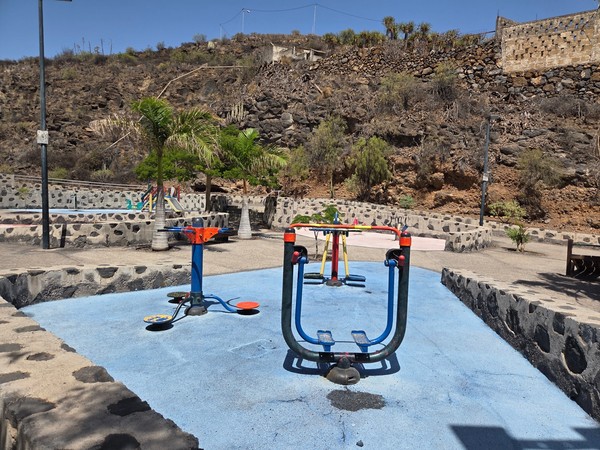 Close view of spinning and balance play equipment on blue safety flooring at La Higuera playground.