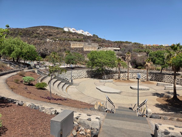 Wide view of the amphitheatre bowl at La Higuera with curved seating tiers, palm trees and open paved stages.