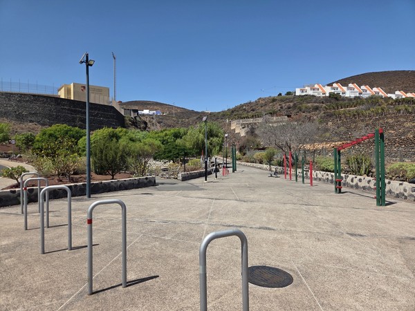 Outdoor fitness area at La Higuera with calisthenics bars, bike racks and open space for body-weight training.