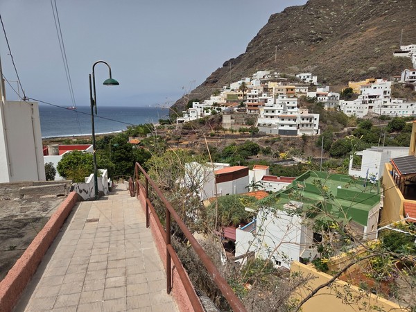 Section of the Paseo Inciensal walkway bordered by stone walls and lamps overlooking the Atlantic.