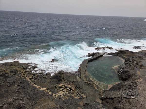 Natural seawater pool (charco) carved in the volcanic rock at La Caleta de Punta Prieta, with steps for safe access.