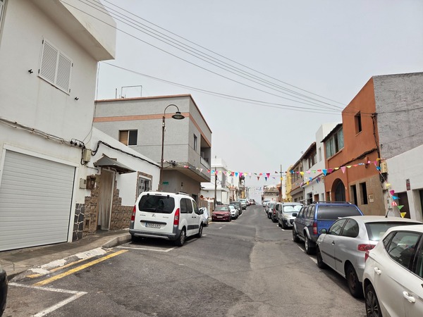 Typical village street in La Caleta de Punta Prieta with bunting and parked cars during festivities.