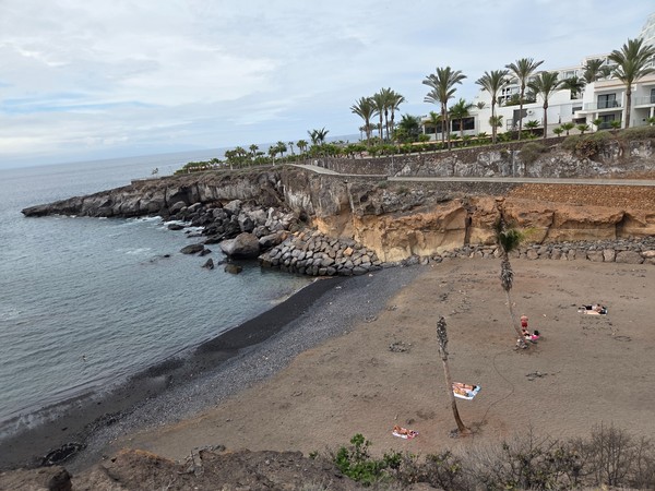 Wide view of Playa Las Galgas cove framed by volcanic cliffs and the Atlantic Ocean in Costa Adeje.