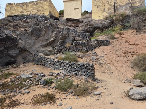 Dry-stone walls and rustic terraces beside the sandy track above the beach at Playa Las Salinas.
