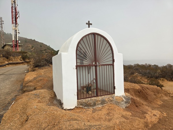 Small white roadside chapel standing by the antenna masts on the ridge.