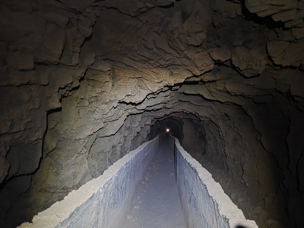Long, dark gallery tunnel with the water canal running inside the mountain.