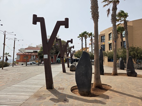 Artistic promenade with basalt boulders, palms and sculptural lighting in Los Abrigos Tenerife.