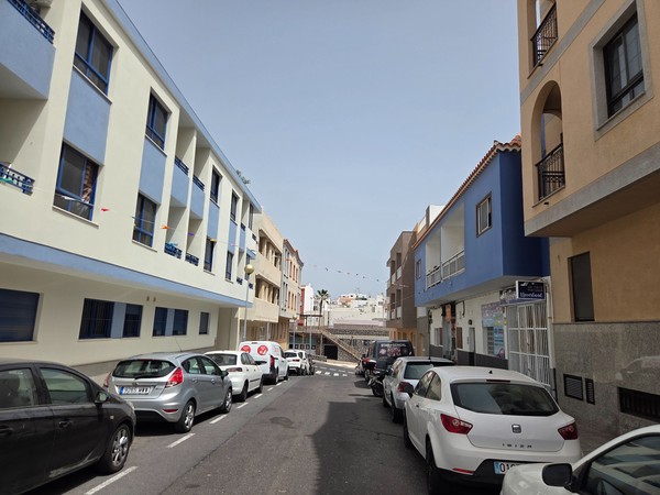 Residential street in Los Abrigos with pastel-colored houses and parked cars.