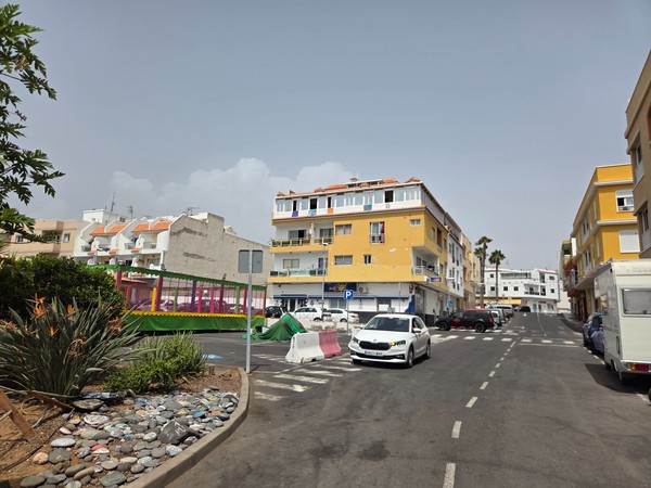 Central road of Los Abrigos with children’s fairground attraction and colorful houses.