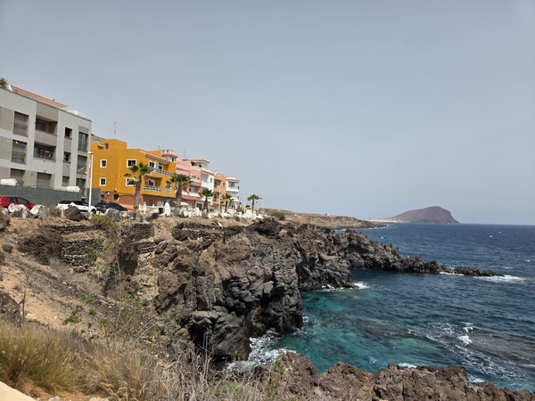 Dark lava cliffs meeting turquoise Atlantic water on the Los Abrigos shoreline.