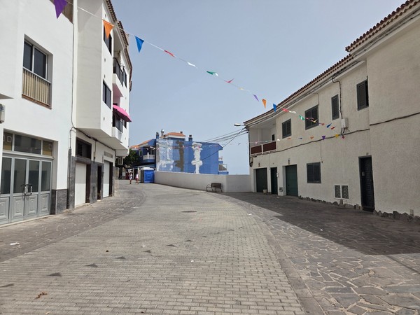 Curved street leading toward the ocean with whitewashed houses and bunting in Los Abrigos.