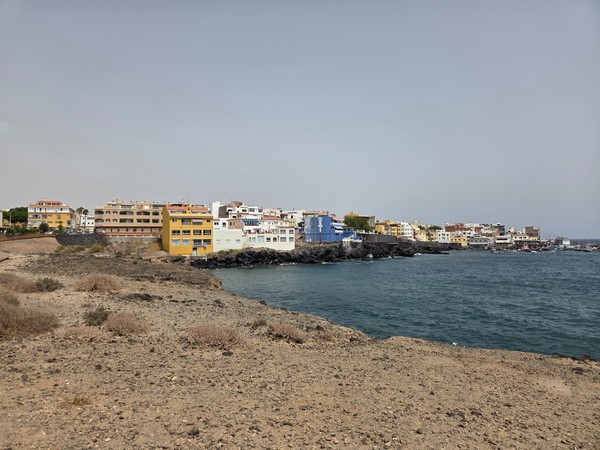 Panoramic view of Los Abrigos coastline with colorful seafront buildings and calm blue ocean.