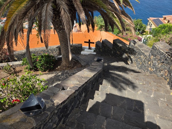 Stone staircase descending to the lower streets with a white cross and sea view in El Sauzal.