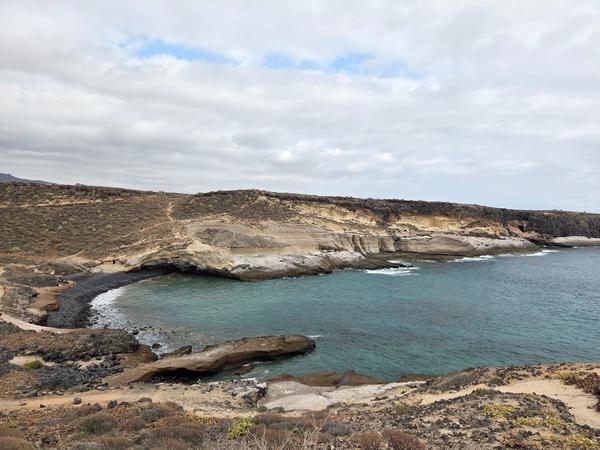 Cliffside view over Playa de los Morteros showing rock formations and hiking trails.