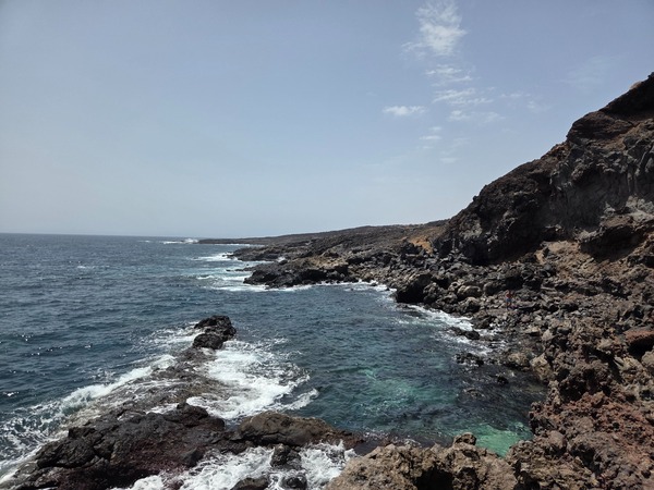 Low tide exposing dark volcanic rocks and shallow pools on the Malpaís de Güímar shoreline.