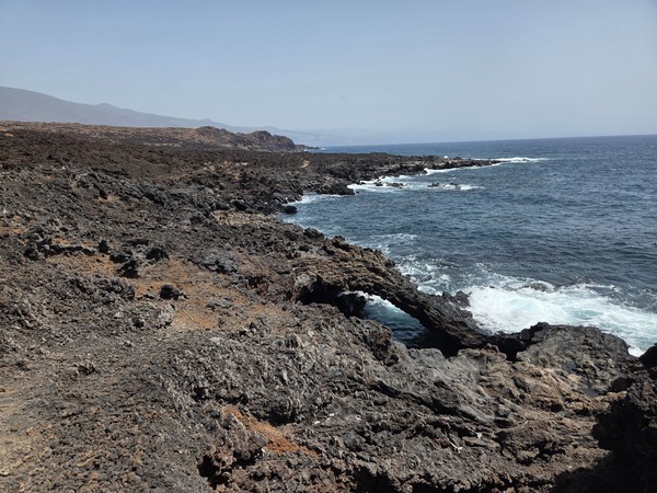 Natural lava arch and rugged cliffs shaped by Atlantic swell on the Malpaís de Güímar coast.