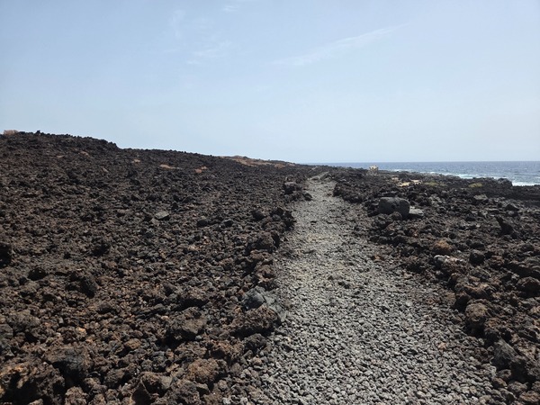 Footpath paved with small lava stones crossing the coastal plain of the Malpaís de Güímar toward the Atlantic.