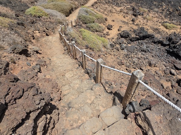 Stone steps with rope handrail descending to a lava cove on the Malpaís de Güímar coast.