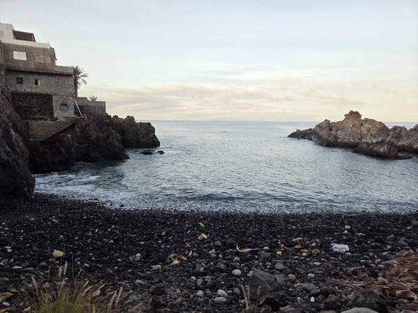 View of Playa Méndez cove with calm ocean water and lava rocks under soft evening light near Alcalá, Tenerife.