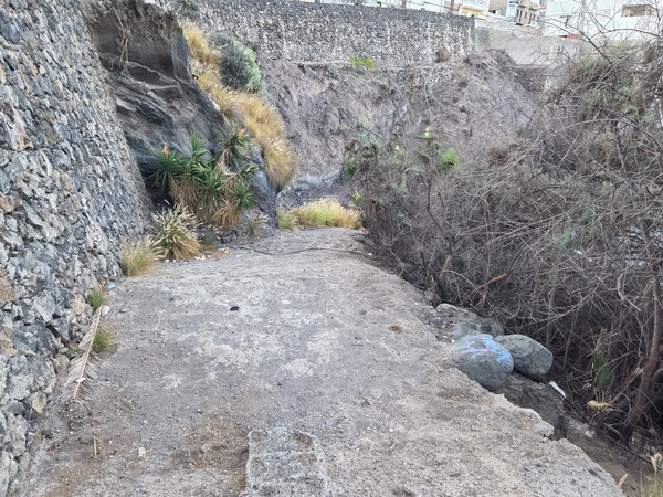 Steep path descending between lava walls and dry plants leading down to Playa Méndez, a hidden beach near Alcalá, Tenerife.