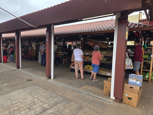 Selection of fruits and vegetables displayed in crates at a stand named Finca La Comarca.