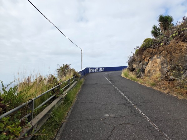 Steep road descending to Mesa del Mar with the name painted on the cliff wall near Tacoronte.