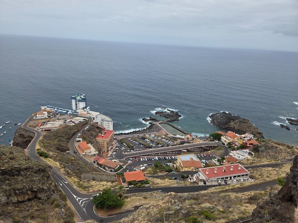 Elevated panoramic view of Mesa del Mar in Tacoronte, Tenerife, showing coastal cliffs, apartment buildings and natural rock pools by the Atlantic Ocean.